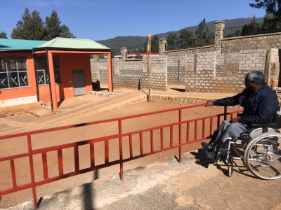 Mies pyörätuolissa katselee esteettömäksi korjattua koulun pihaa Etiopiassa