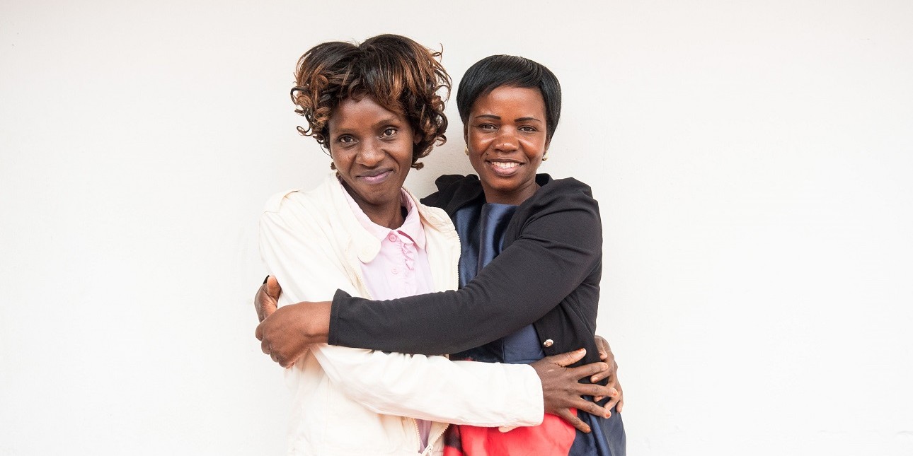 Kaksi sambialaista naistaa halaa toisiaan