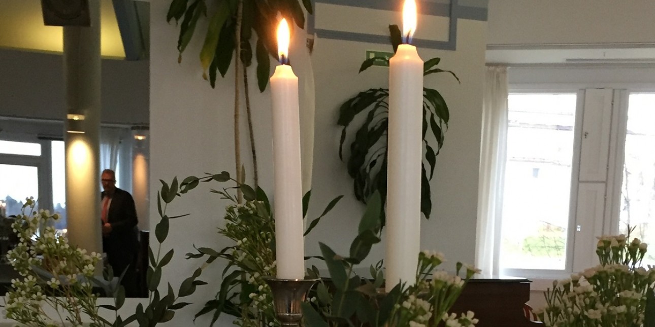 2 kynttilää ja maljakoissa kukkia