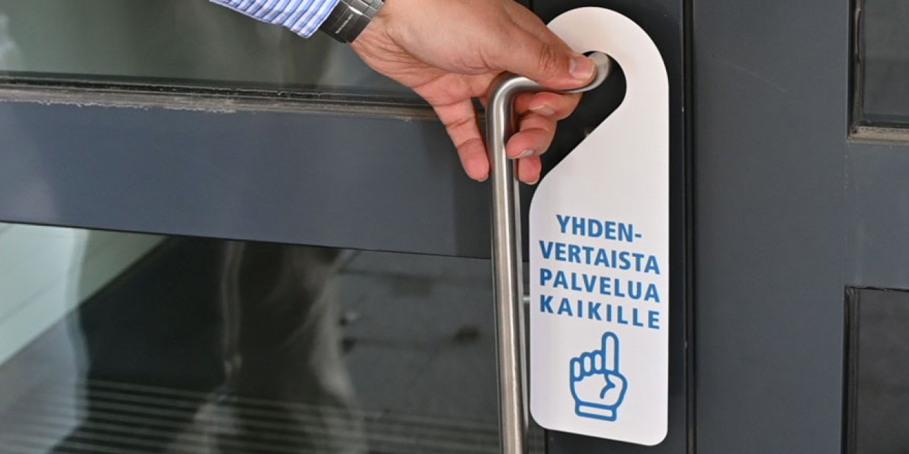 Yhdenvertaista palvelu kaikille -oviriippu ovessa. Kuvituskuva.