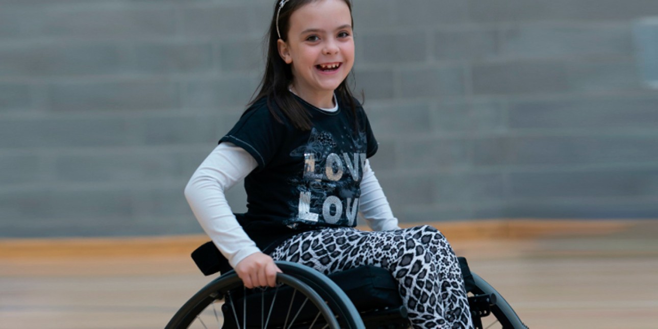 hymyilevä tyttö pyörätuolissa