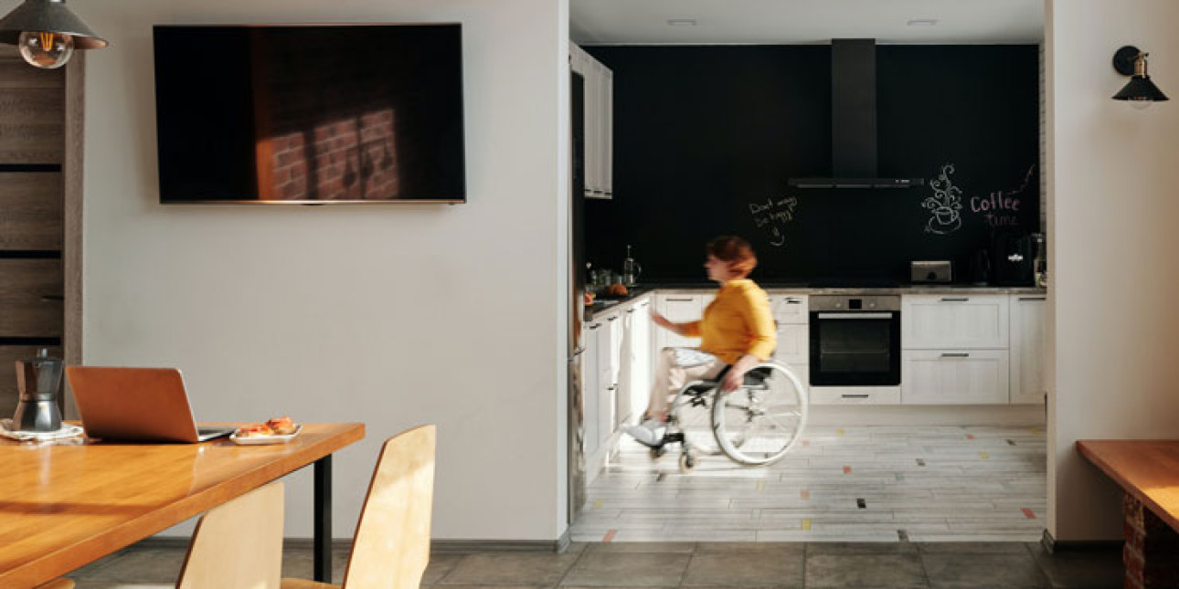 Asukas pyörätuolissa puuhailemassa modernissa keittiössä