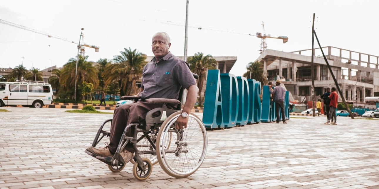 Etiopialainen mies liikkumassa pyörätuolilla aukiolla Addis Abebassa.