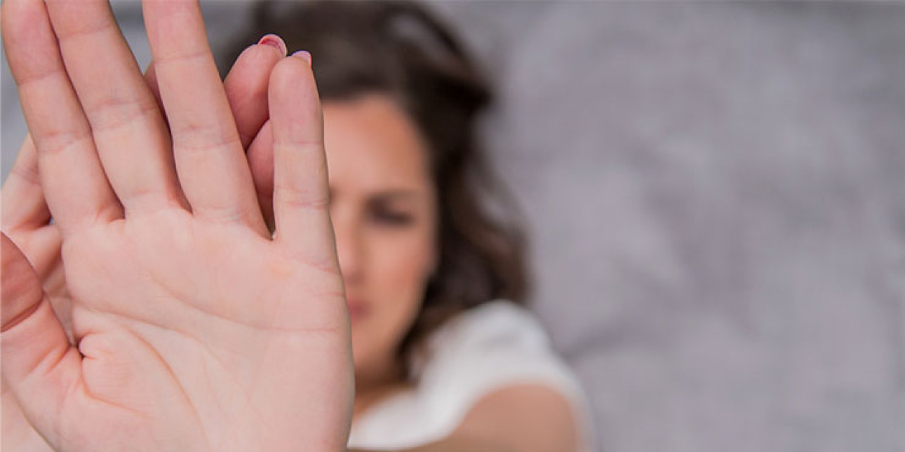 Kuvassa nainen torjuvana käsi edessä.