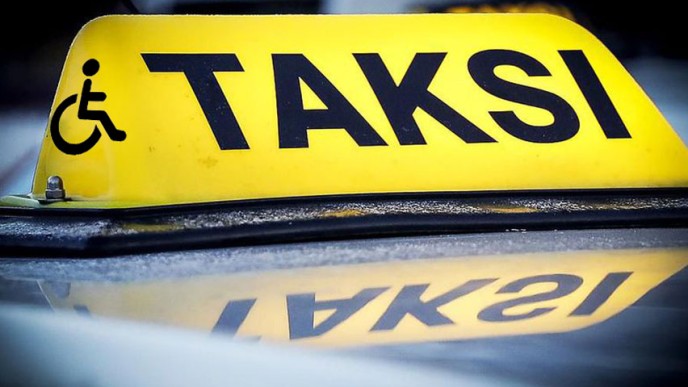Kuvassa taksin katolla oleva taksikyltti ja inva-logo.
