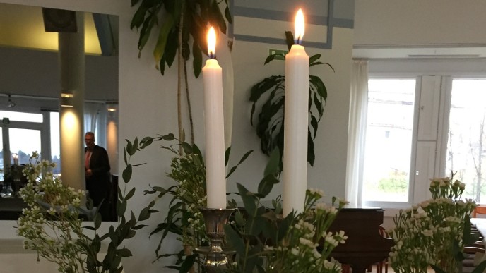 2 kynttilää ja maljakoissa kukkia