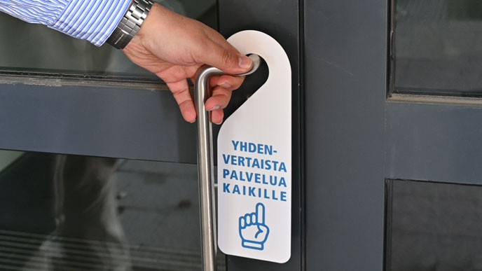 Yhdenvertaista palvelu kaikille -oviriippu ovessa. Kuvituskuva.