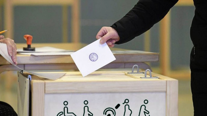 Äänestäjä pudottaa äänestylipukkeen vaalipaikan laatikkoon
