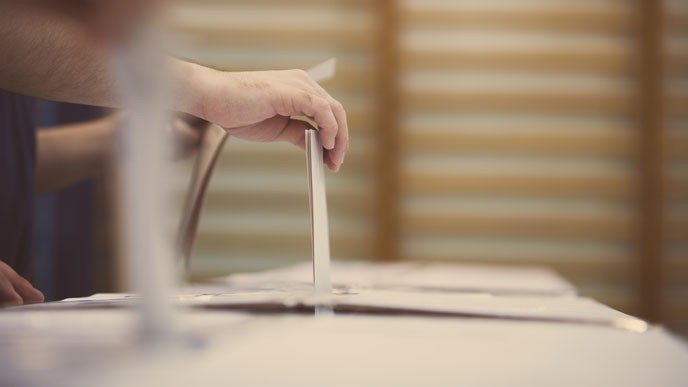 Äänestyslippu pudotetaan vaaliuurnaan (kuvituskuva).