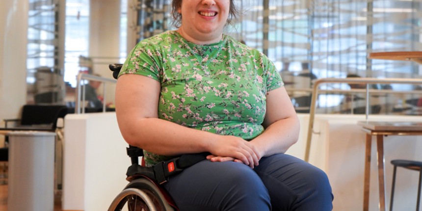 Invalidiliiton nuori aktiivi Selda istuu etualalla ja hymyilee kameraan.